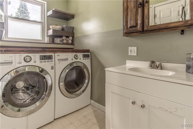 laundry area with cabinet space, a sink, baseboards, light floors, and washer and clothes dryer
