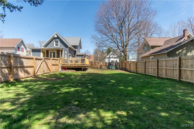view of yard with a playground, a wooden deck, and a fenced backyard
