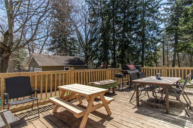 wooden terrace featuring area for grilling and outdoor dining area