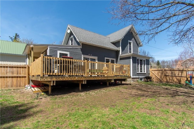 back of property featuring a shingled roof, a wooden deck, and fence