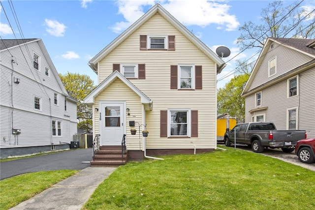 traditional-style house featuring central air condition unit, entry steps, and a front lawn
