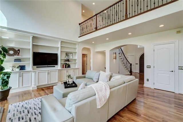 4 Windscape Park, Pittsford, NY 14534 - living room featuring arched walkways, light wood-style flooring, recessed lighting, a towering ceiling, and stairway