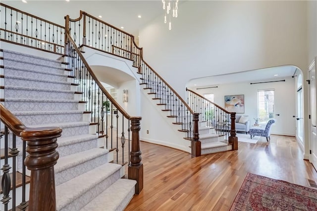 4 Windscape Park, Pittsford, NY 14534 - staircase featuring arched walkways, baseboards, wood finished floors, and a towering ceiling