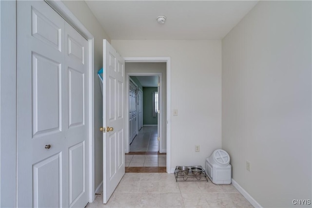 hall featuring light tile patterned floors and baseboards