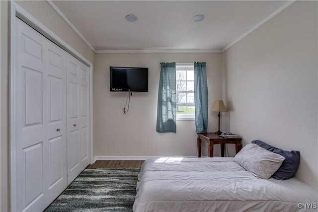 bedroom featuring a closet, baseboards, crown molding, and wood finished floors