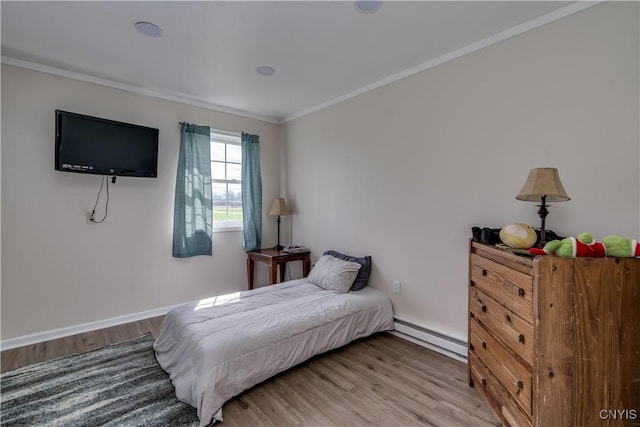 bedroom featuring crown molding, baseboards, baseboard heating, and wood finished floors