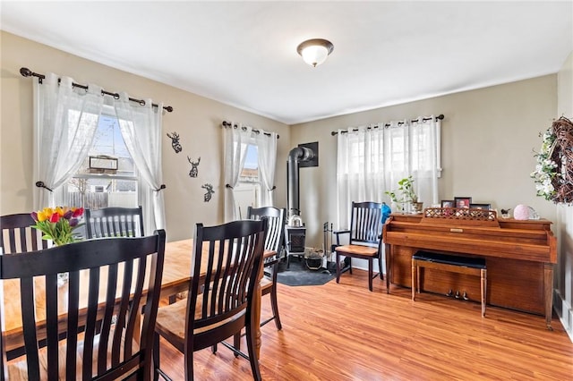dining space with a wood stove and light wood finished floors