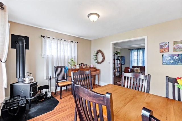 dining space with a wood stove and wood finished floors