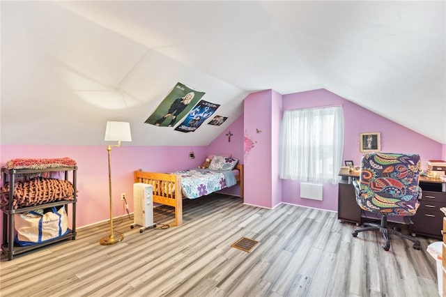 bedroom with wood finished floors and lofted ceiling