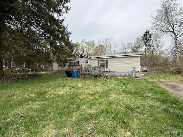 rear view of property featuring a wooden deck, a yard, and metal roof