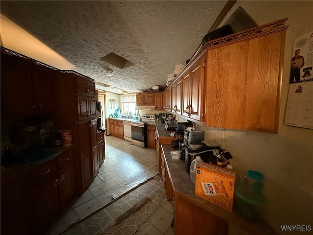 kitchen featuring dark countertops, dishwasher, a textured ceiling, brown cabinetry, and stainless steel electric stove