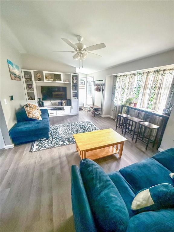 living room with a ceiling fan, baseboards, and wood finished floors