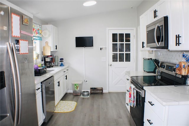 kitchen featuring wood finished floors, appliances with stainless steel finishes, backsplash, and white cabinets