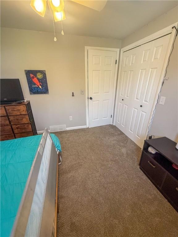bedroom featuring a ceiling fan, visible vents, baseboards, a closet, and carpet flooring