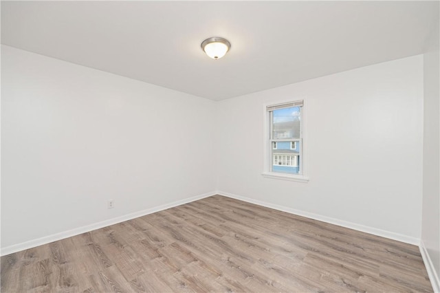 spare room with baseboards and light wood-style floors