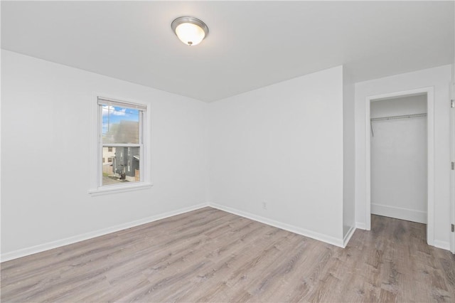 unfurnished bedroom featuring baseboards, wood finished floors, and a closet