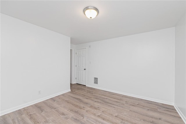 empty room with visible vents, light wood-style floors, and baseboards