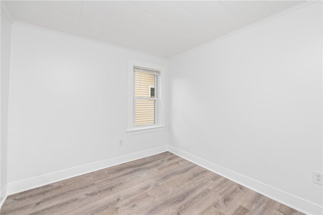 empty room featuring crown molding, baseboards, and light wood-style floors