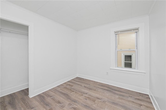 unfurnished bedroom featuring crown molding, baseboards, wood finished floors, and a closet
