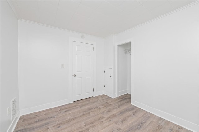 empty room with baseboards, ornamental molding, wood finished floors, and visible vents