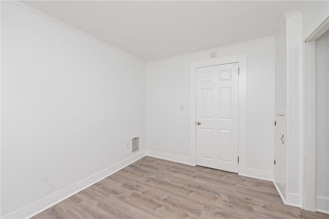 empty room featuring crown molding, baseboards, visible vents, and light wood-type flooring