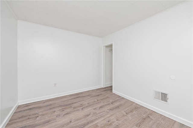 unfurnished room with baseboards, visible vents, and wood finished floors