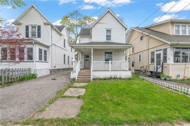 view of front of property with fence, a porch, and a front lawn
