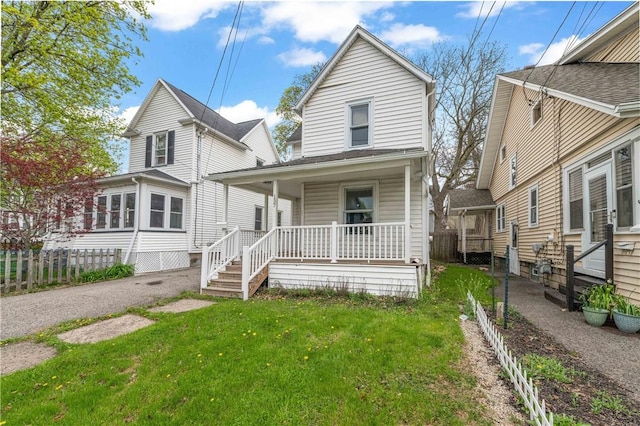 view of front of house featuring fence, covered porch, and a front yard