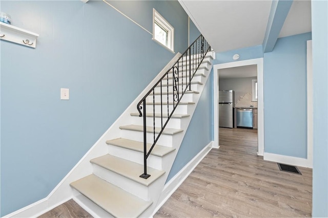 stairs featuring baseboards, wood finished floors, and visible vents