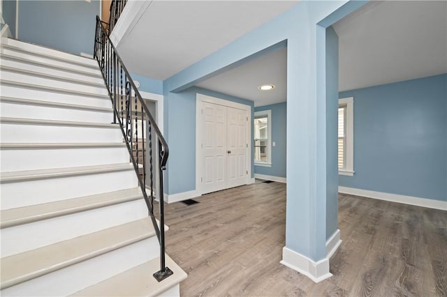 foyer entrance featuring stairway, baseboards, wood finished floors, and visible vents