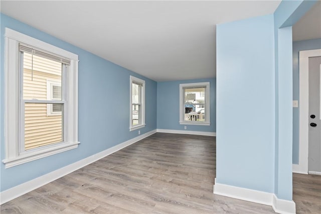 spare room with baseboards and wood finished floors