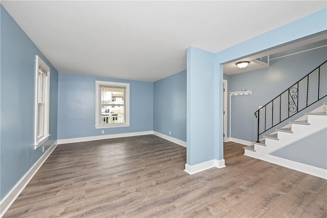 unfurnished living room with baseboards, stairs, and wood finished floors