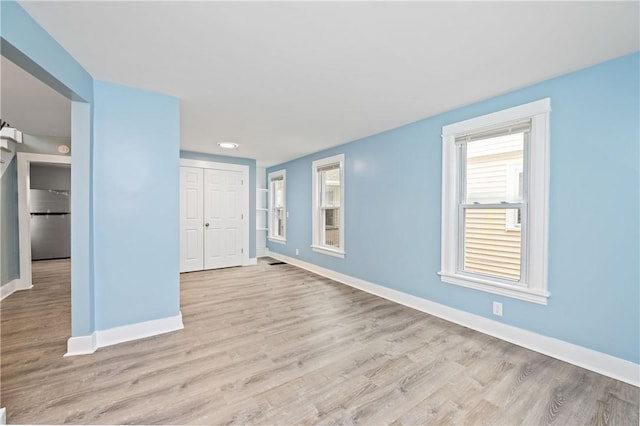 unfurnished living room with baseboards, visible vents, and wood finished floors