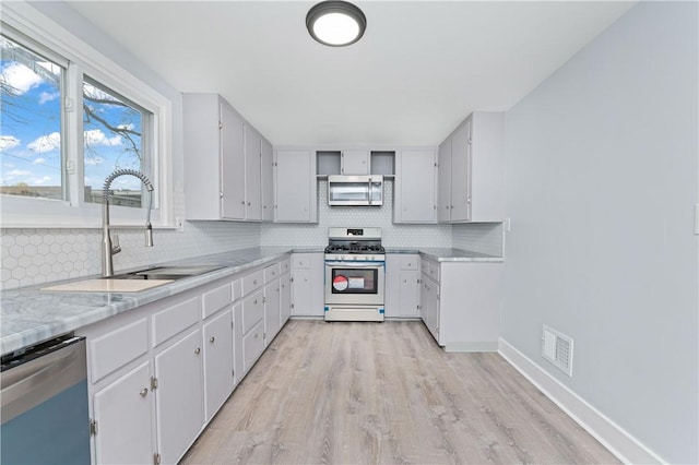 kitchen with decorative backsplash, visible vents, appliances with stainless steel finishes, open shelves, and a sink