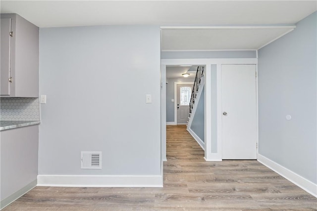 interior space featuring visible vents, tasteful backsplash, light wood-type flooring, light countertops, and baseboards