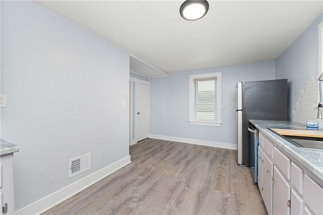 kitchen with visible vents, dishwasher, baseboards, white cabinets, and light wood-style floors