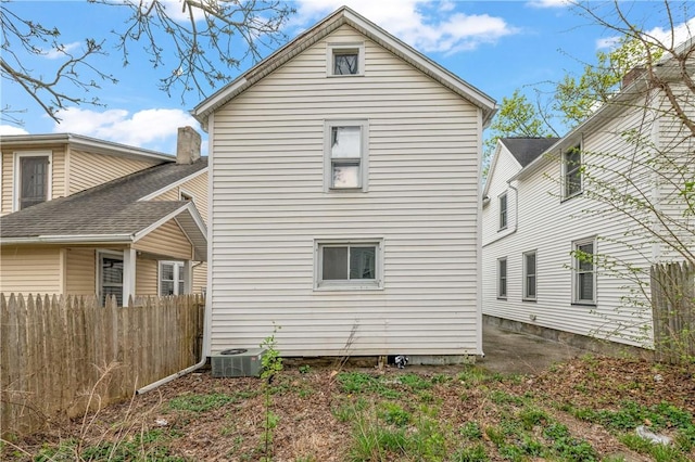 rear view of house featuring fence and central AC unit