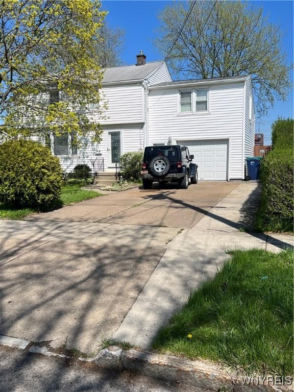 view of property exterior with a chimney, an attached garage, and driveway