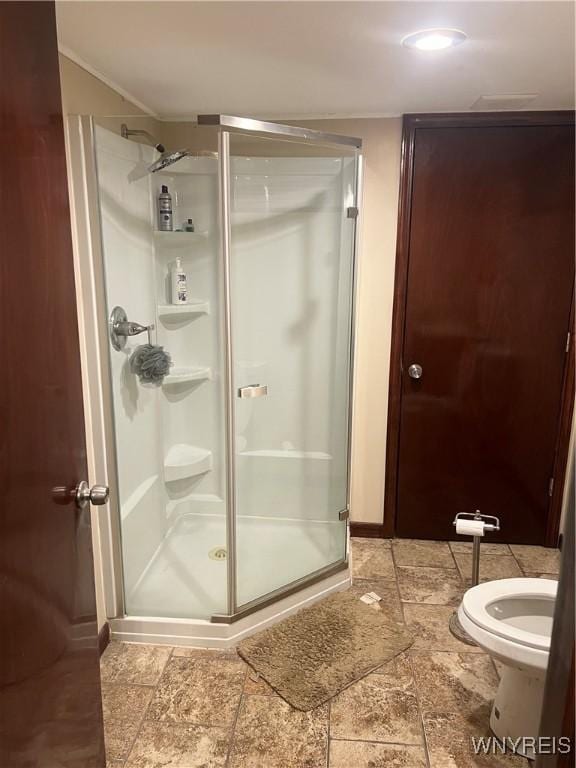 bathroom with ornamental molding, a stall shower, and toilet