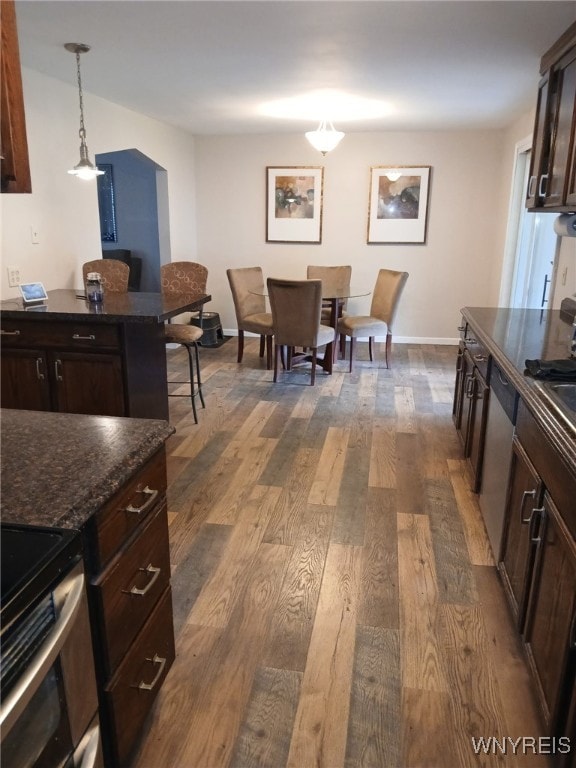 kitchen featuring pendant lighting, dark brown cabinets, baseboards, dark wood-style floors, and appliances with stainless steel finishes