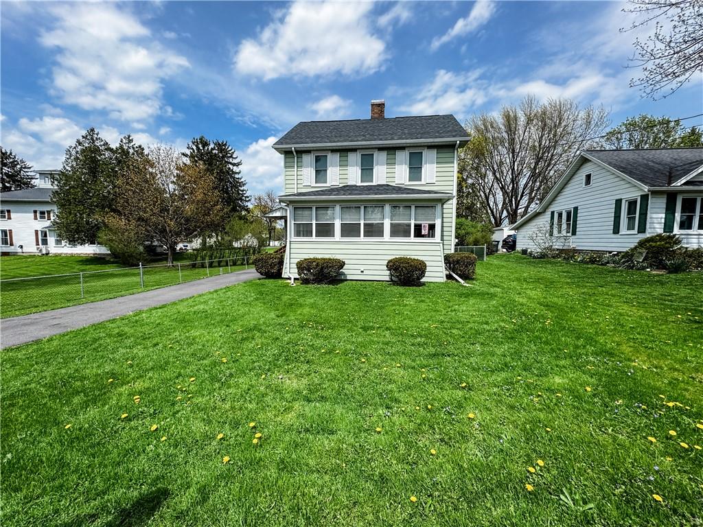 traditional-style home featuring fence, a chimney, a front yard, and aphalt driveway