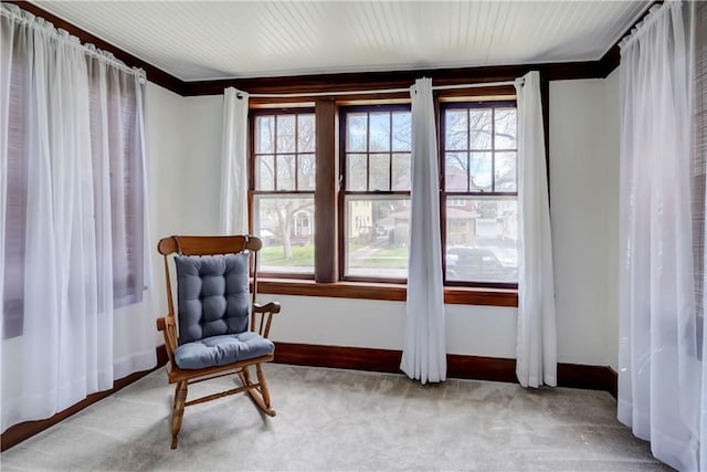 living area featuring baseboards, ornamental molding, and carpet