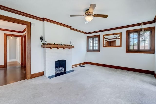 unfurnished living room with ceiling fan, a fireplace, baseboards, ornamental molding, and carpet flooring