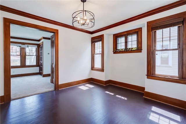 spare room featuring a healthy amount of sunlight, baseboards, an inviting chandelier, and crown molding
