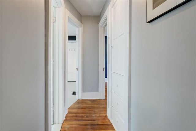 corridor featuring baseboards, attic access, and wood finished floors
