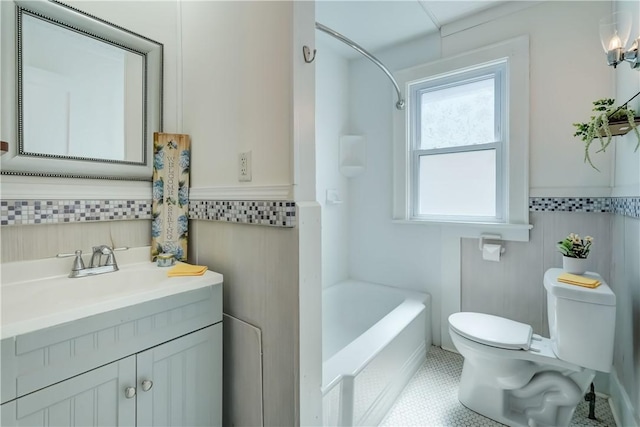 full bathroom with vanity, shower / bathtub combination, toilet, tile walls, and a wainscoted wall