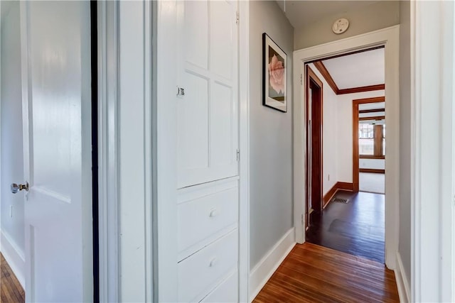 hall featuring baseboards, ornamental molding, and dark wood-style flooring