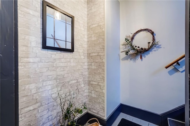 bathroom featuring baseboards and brick wall