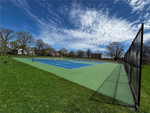 view of tennis court featuring fence and a yard