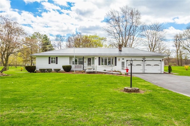 ranch-style home featuring a front lawn, aphalt driveway, a garage, covered porch, and metal roof